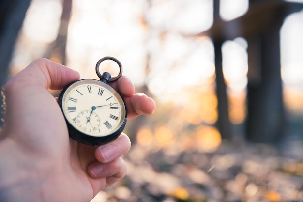 Le temps passe par une montre vintage à l'extérieur en bois et feuilles de poche