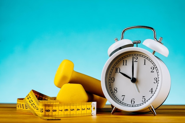 Temps pour l'horloge d'entraînement et l'haltère avec un fond bleu coloré