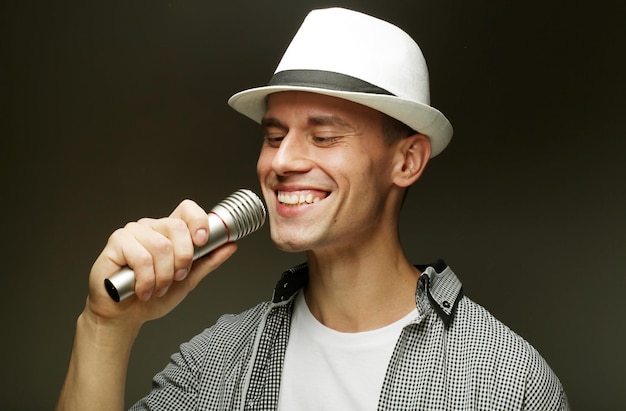 Temps pour le karaoké Jeune homme chantant avec microphone