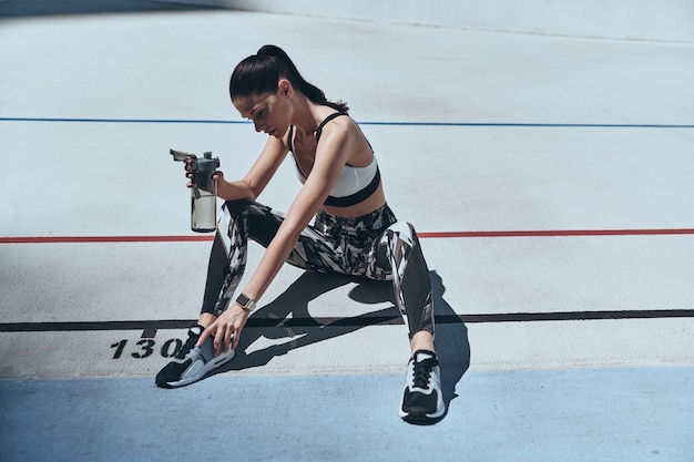 Temps de repos. Vue de dessus de la jeune femme en vêtements de sport relaxant