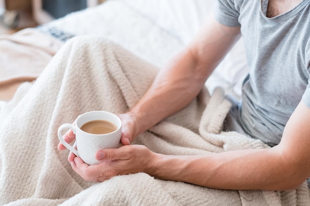 Temps de se réveiller Café au lit Mode de vie de l'homme Mains autour d'une tasse de latte Tranquille avec boisson préférée