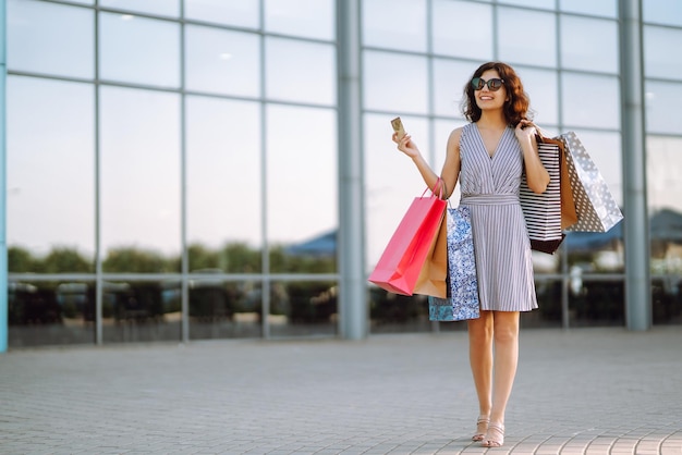 Temps de shopping Jeune femme avec des sacs à provisions près du centre commercial Consommation vente achats