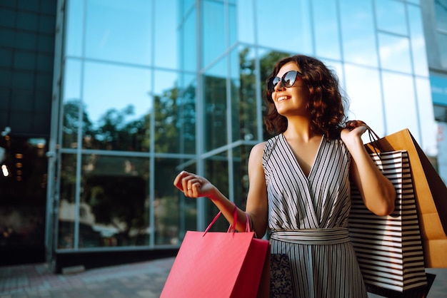 Photo temps de shopping jeune femme avec des sacs à provisions près du centre commercial consommation vente achats