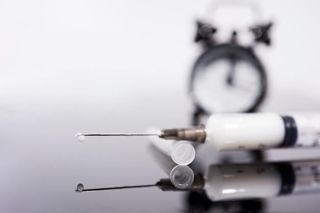 Photo temps de vaccination. vaccin en flacon avec seringue sur fond d'horloge