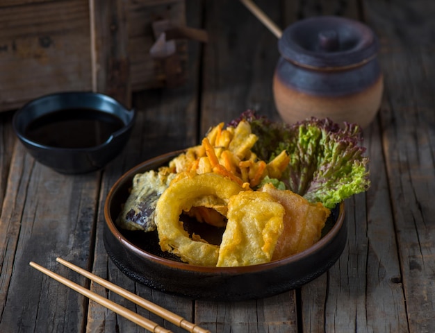 Photo tempura de légumes servi dans un plat isolé sur la vue de côté de fond en bois