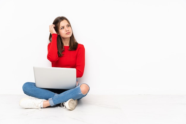 Tenaager girl travaillant avec pc sur mur blanc ayant des doutes