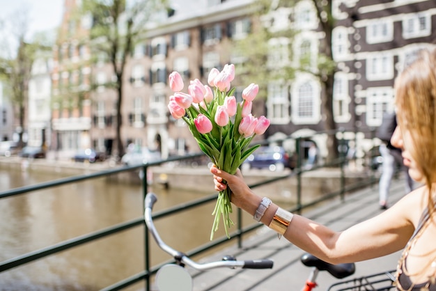 Tenant un bouquet de tulipes roses sur le canal d'eau et le fond des bâtiments à Amsterdam