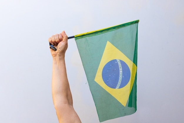 Tenant le drapeau du Brésil isolé sur fond blanc. Drapeau et image de concept de jour de l'indépendance.