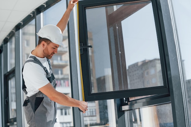 Tenant la fenêtre Le réparateur travaille à l'intérieur dans la salle moderne