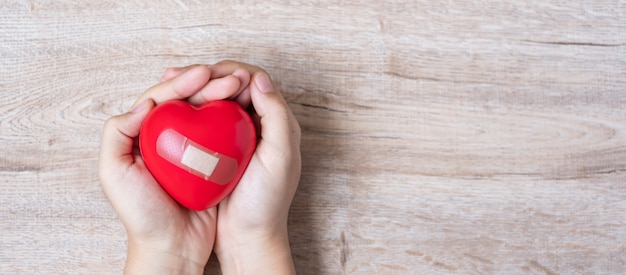 tenant en forme de coeur rouge sur fond en bois. Soins de santé