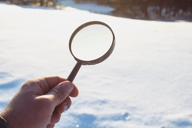 Tenant une loupe sur fond de neige