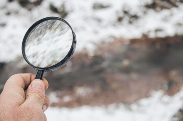 Tenant une loupe sur le fond d'une rivière gelée