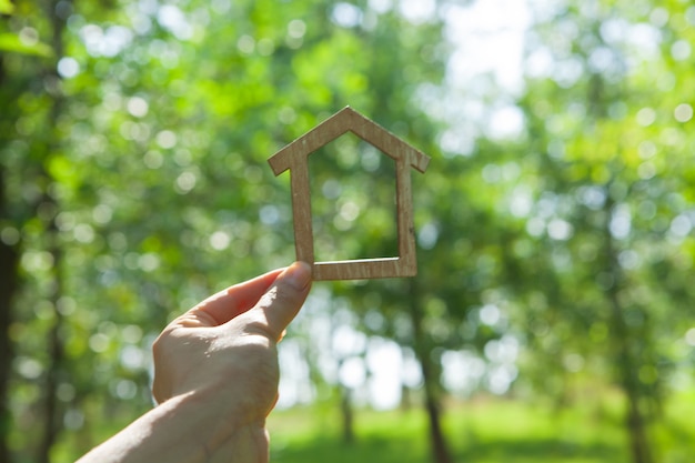 Tenant une maison à la main sur le fond de la nature