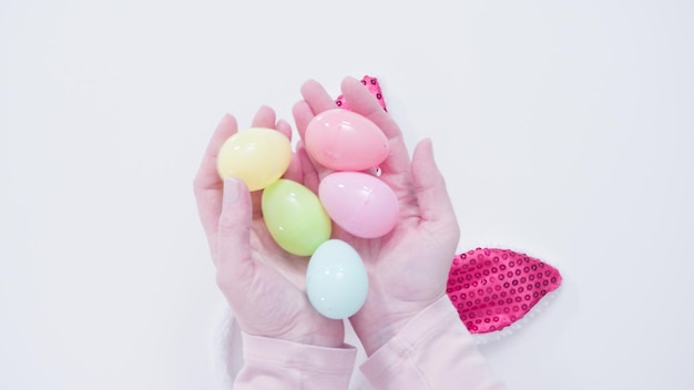 Tenant des oeufs en plastique de Pâques sur un fond blanc.