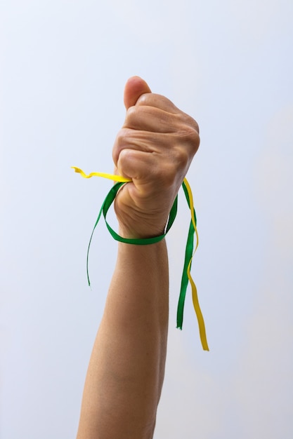 Tenant des rubans verts et jaunes du drapeau du Brésil isolé sur fond blanc. Drapeau et image de concept de jour de l'indépendance.