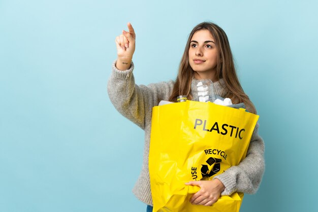 Tenant un sac plein de bouteilles en plastique à recycler sur bleu isolé touchant sur écran transparent