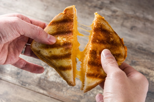 Tenant un sandwich au fromage dans ses mains