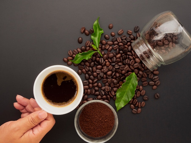 Tenant une tasse de café sur les grains de café.