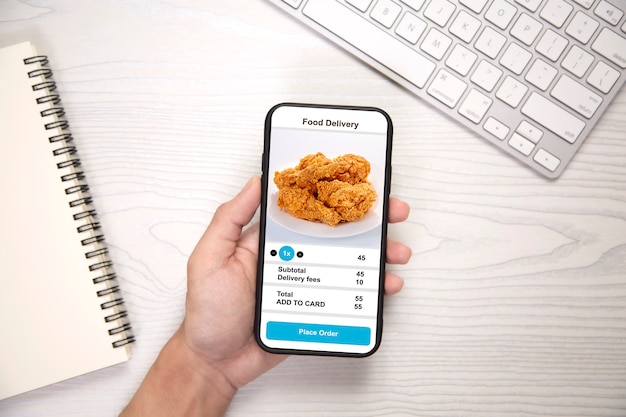 Tenant le téléphone avec la nourriture de livraison d'application