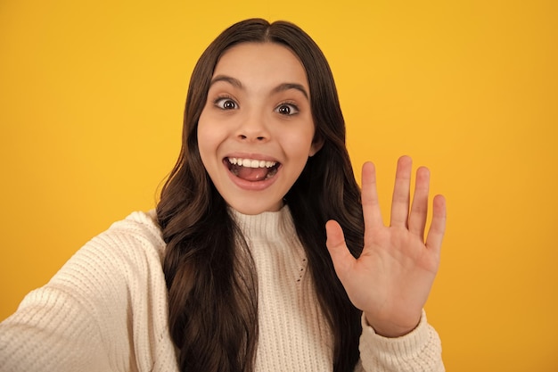 Tendance beau modèle adolescent faisant selfie posant sur fond de studio jaune Mode adolescent Visage heureux émotions positives et souriantes d'une adolescente