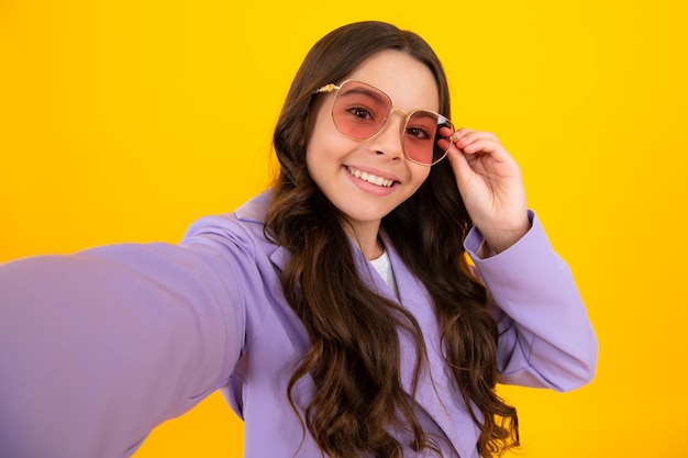 Tendance beau modèle adolescent faisant selfie posant sur fond de studio jaune