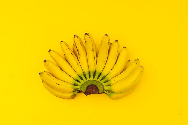 Une tendance mûre prête à manger un tas de mini bananes moche avec des points noirs sur une surface jaune