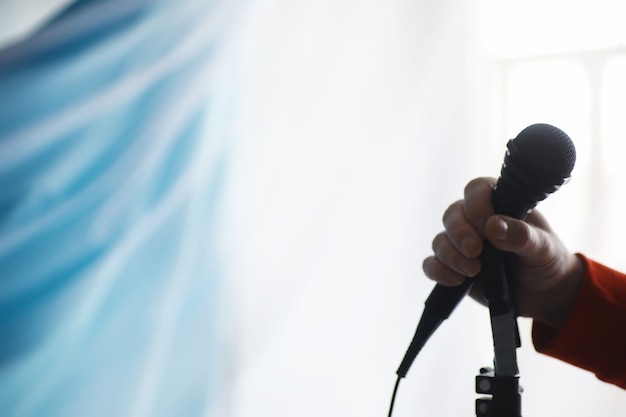 Tenez-vous debout avec un microphone. L'homme tient un microphone sur un trépied. Performance de l'artiste avec un microphone. Scène avec un micro.