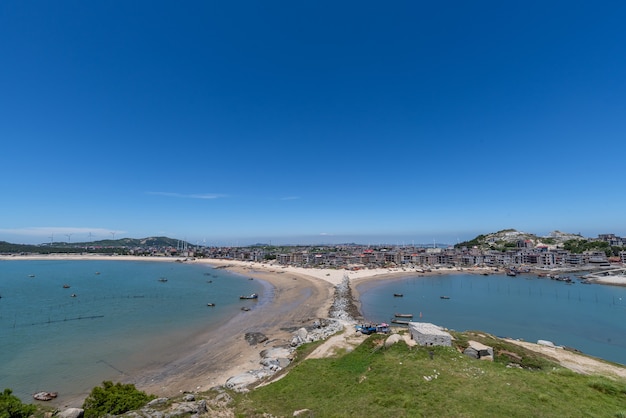 Tenez-vous haut et regardez le paysage marin sous le ciel bleu, l'eau bleue, les vagues blanches et les rochers noirs