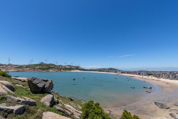 Tenez-vous haut et regardez le paysage de la mer sous le ciel bleu l'eau bleue les vagues blanches et les rochers noirs