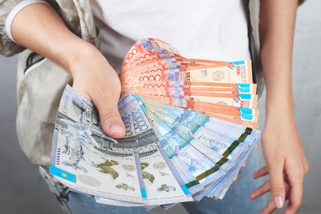 Tenge. Une fille en t-shirt blanc tenant beaucoup de billets kazakhs en gros plan.