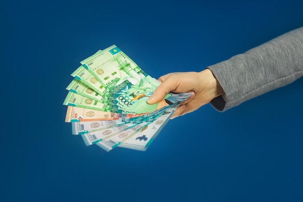 Tenge Monnaie nationale du Kazakhstan en main sur fond bleu Mise au point sélective