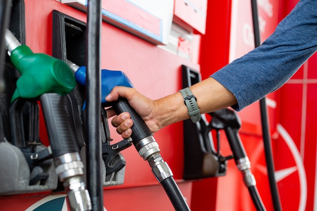 Tenir la buse de pétrole pour remplir votre carburant dans l'entretien du moteur. Station de pompage en libre-service avec vous-même. Service essence automobile.