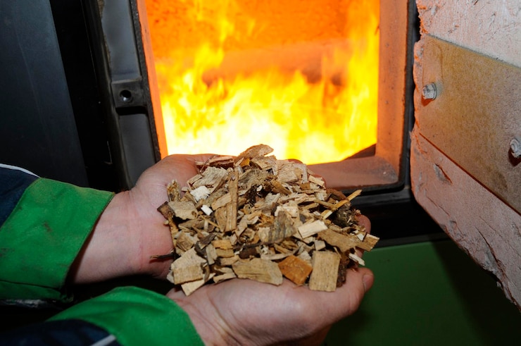Photo tenir des copeaux de bois dans les mains brûler du feu dans le four à l'arrière chauffer avec des coupes de bois à la maison