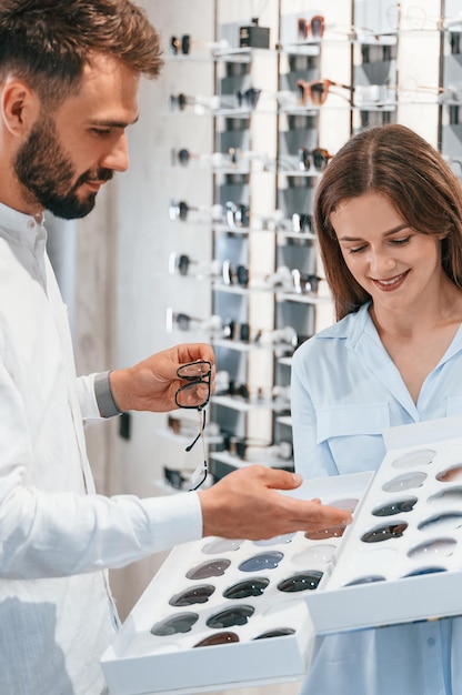 Tenir des lentilles remplaçables Homme et femme dans le magasin de lunettes Aider à choisir le produit