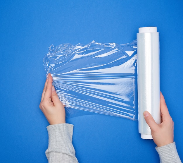 Photo tenir à la main un grand rouleau de film transparent blanc enroulé pour emballer les aliments