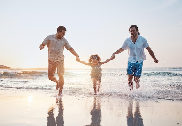 Tenir la main sur la plage et un couple gay avec un enfant heureux ou des vacances avec du temps de qualité pour célébrer ou des liens queer personnes hommes ou enfants avec des vacances à la mer ou une famille avec amour ou lgbtq