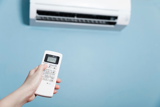 Photo tenir la télécommande du climatiseur en main, gros plan d'une main tenant la télécommande du climatiseur blanc.