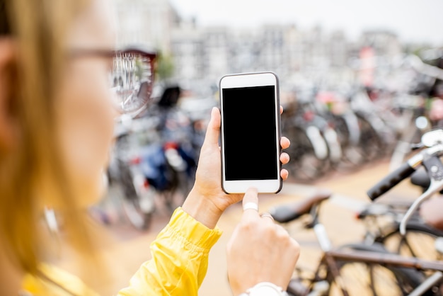 Tenir un téléphone intelligent avec un écran vide pour copier-coller sur l'arrière-plan du parking à vélos