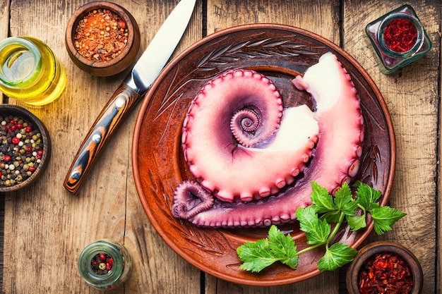 Tentacule de poulpe cru avec des légumes sur la table de la cuisine