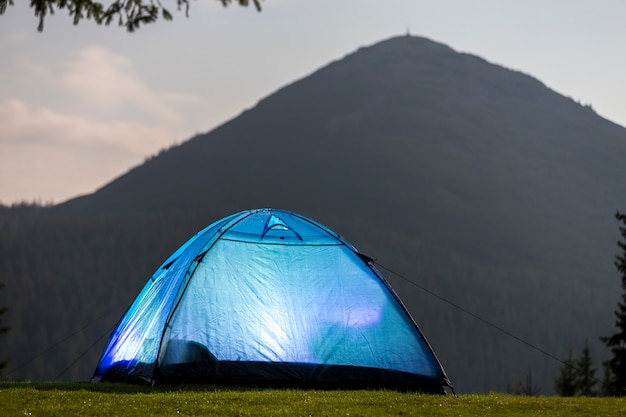 Tente bleue sur la forêt de compensation sur fond de montagne lointaine.