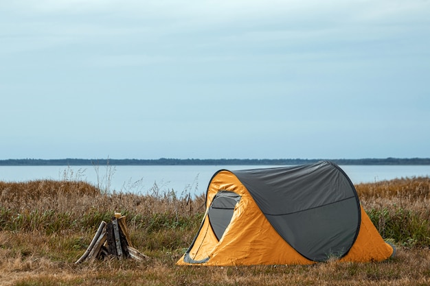 Tente de camping en orange nature et le lac. voyages, tourisme, camping.