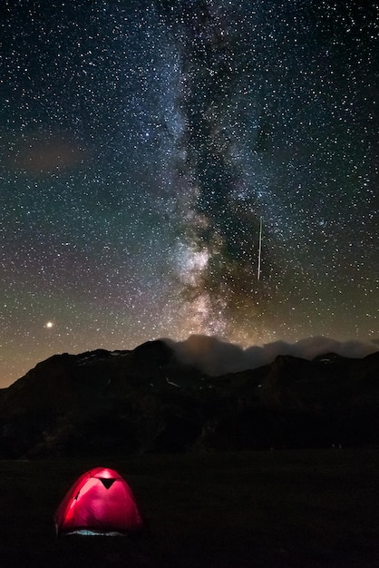 Tente éclairée sur le champ contre le champ d'étoiles