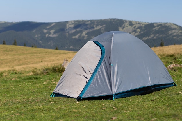 Photo une tente grise debout dans une clairière sur fond de montagnes.