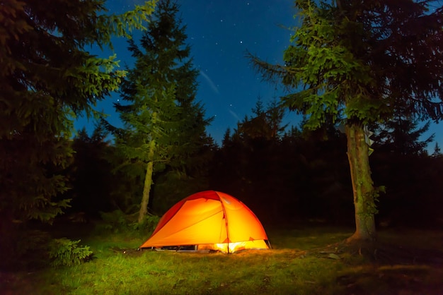 Tente illuminée dans la forêt de nuit