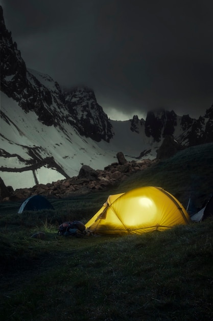 Tente jaune sur le fond des crêtes de montagne dans la neige la nuit