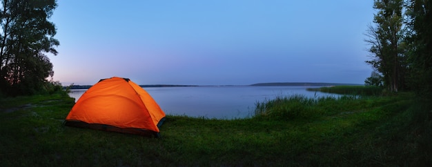 Tente orange au bord du lac