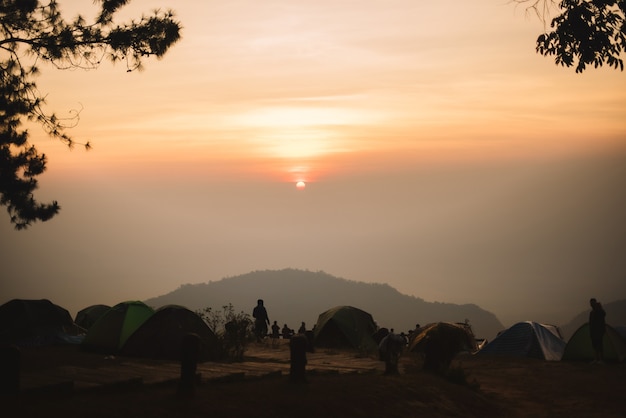 Tente orange hébergement de touristes pour regarder la montagne noire de brume avec vue sur le lever du soleil brumeux bof