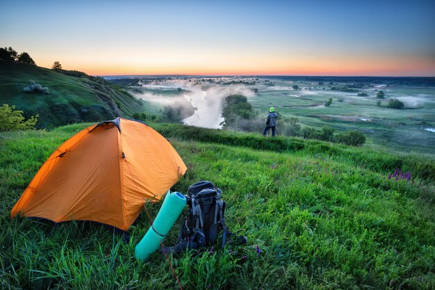 Tente orange et sac à dos sur la colline avec les touristes