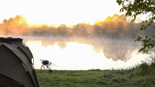 Tente de pêche à la carpe et canes sur le fond d'un lac ou d'une rivière et de la nature le matin