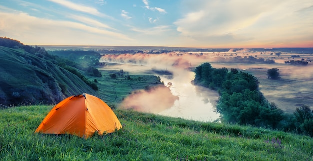 Tente touristique orange sur la colline avec de l'herbe verte